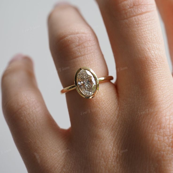 a woman's hand with a diamond ring on top of her finger, showing the center stone