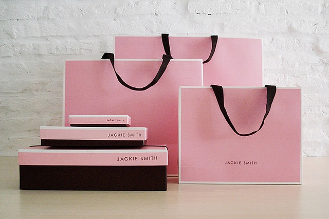 three pink shopping bags sitting next to each other on top of a white countertop