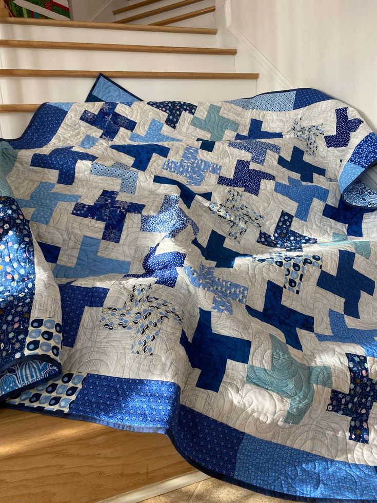 a blue and white quilt sitting on top of a wooden floor next to a stair case