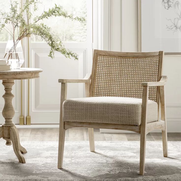 a wooden chair sitting next to a table with a vase on it and a plant in the corner