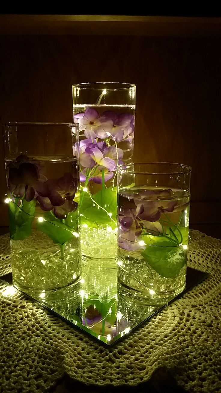 three glasses filled with water and flowers on top of a table