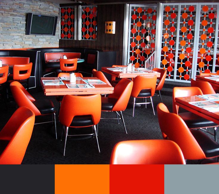 the interior of a restaurant with orange and red chairs