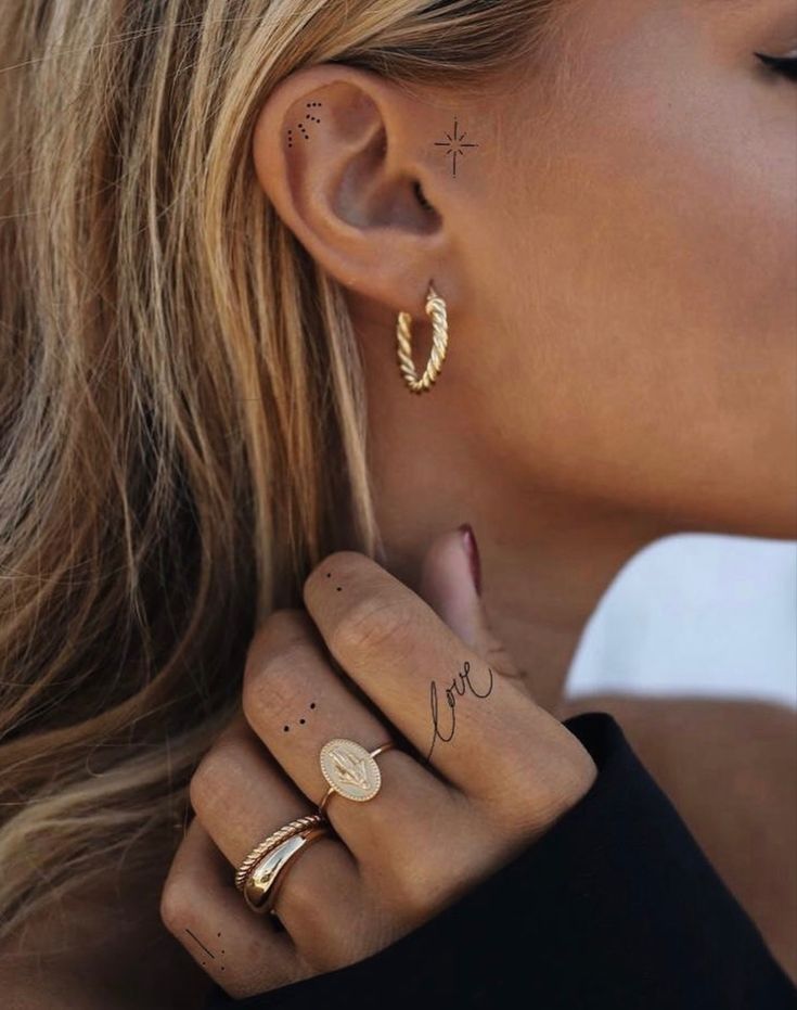 a woman with two gold rings and one has a star tattoo on her left ear