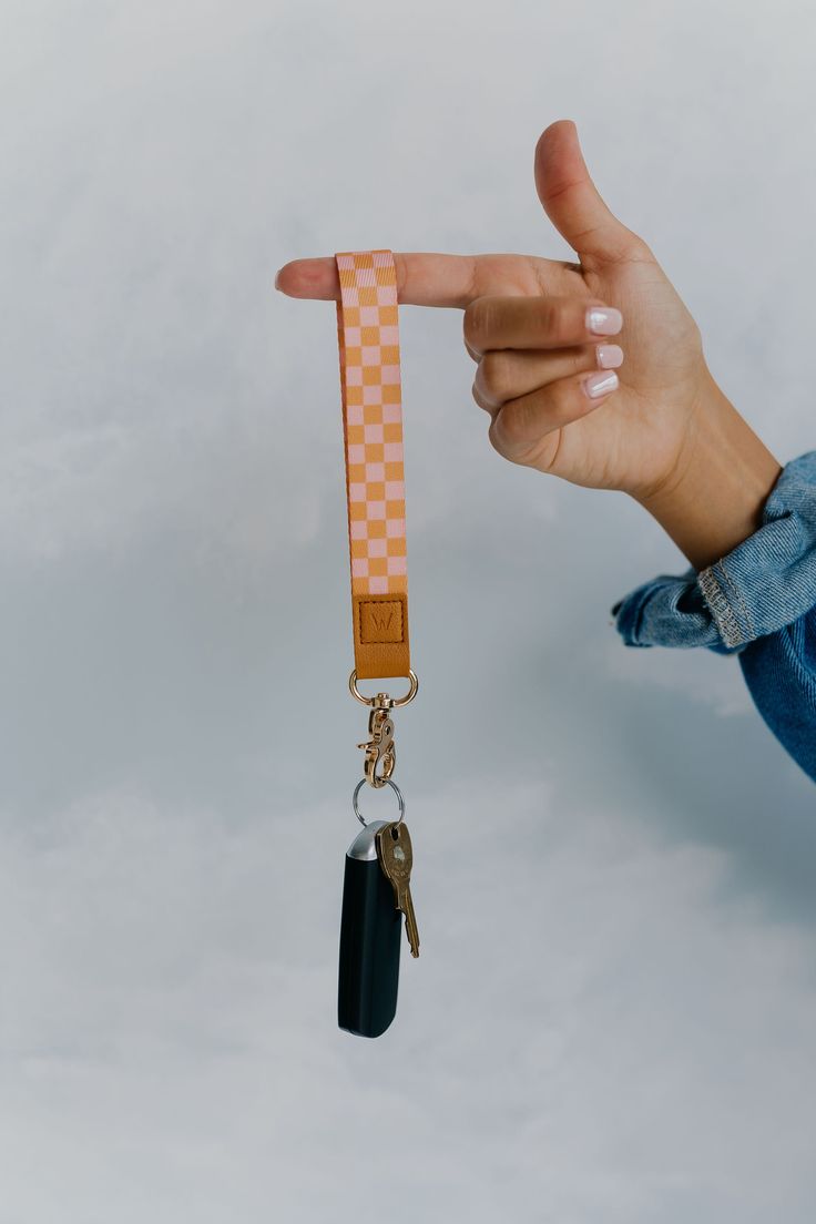 a hand holding a keychain that has a checkered design on it