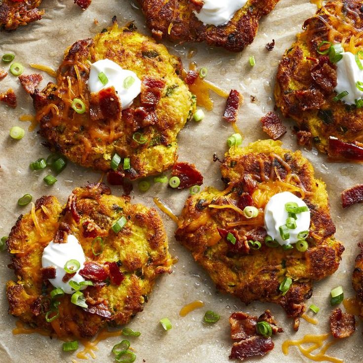 several potato cakes with sour cream on top and green onions around the edges, sitting on wax paper