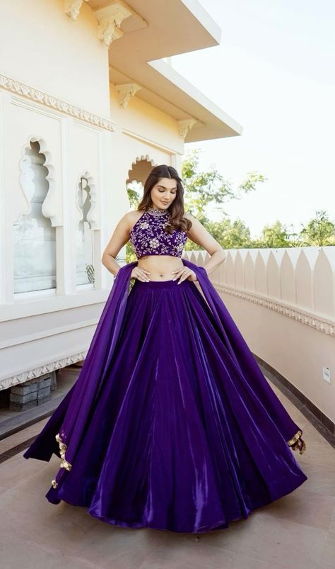 a woman standing in front of a building wearing a purple dress