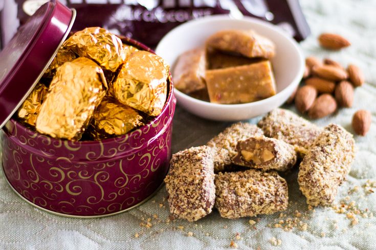 nuts, almonds and chocolate are on the table next to a tin with gold bars in it