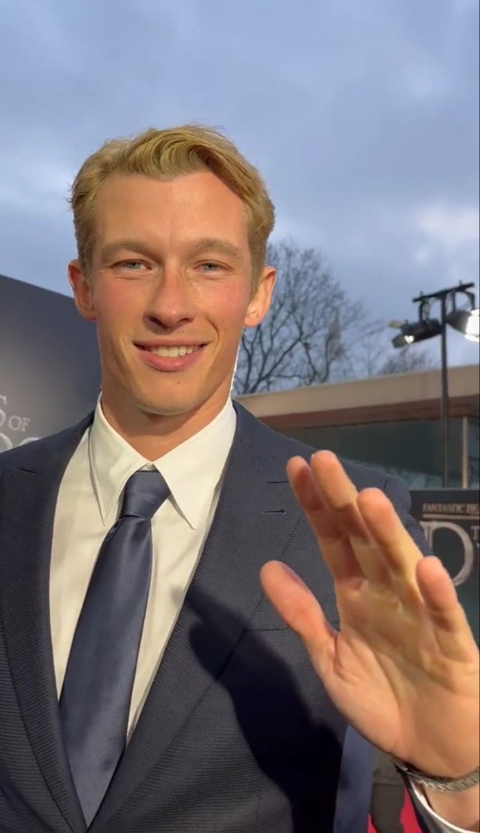 a man in a suit and tie making a hand gesture