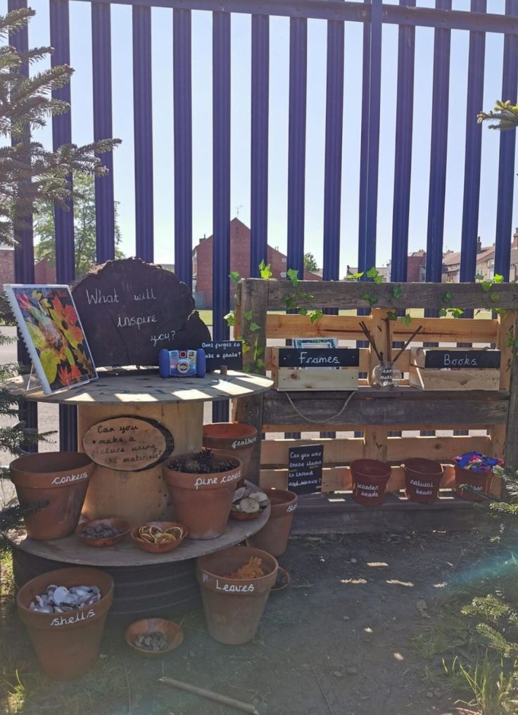 several pots are stacked on top of each other in front of a fence and sign