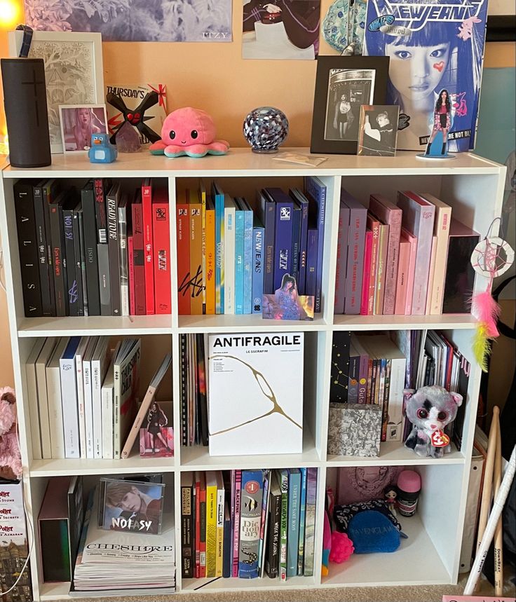 a bookshelf filled with lots of books and stuffed animals on top of it