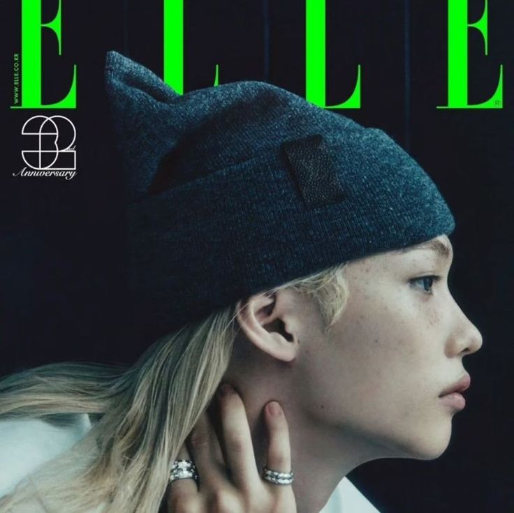 a woman with blonde hair wearing a beanie and earrings on the cover of a magazine