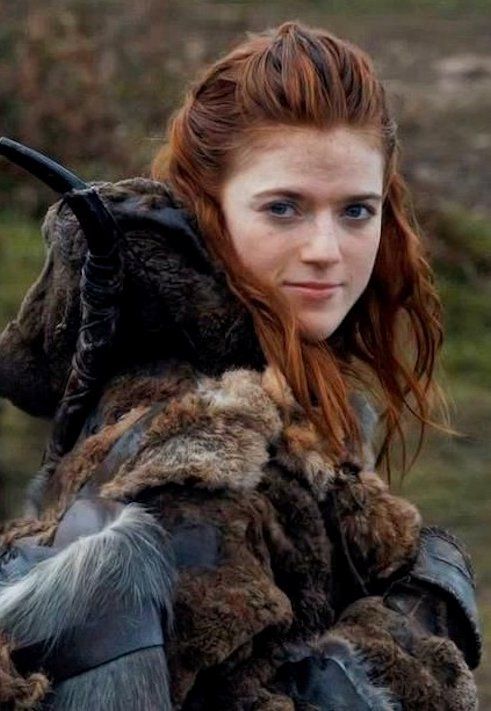 a woman with long red hair wearing a fur coat and holding a bird on her shoulder