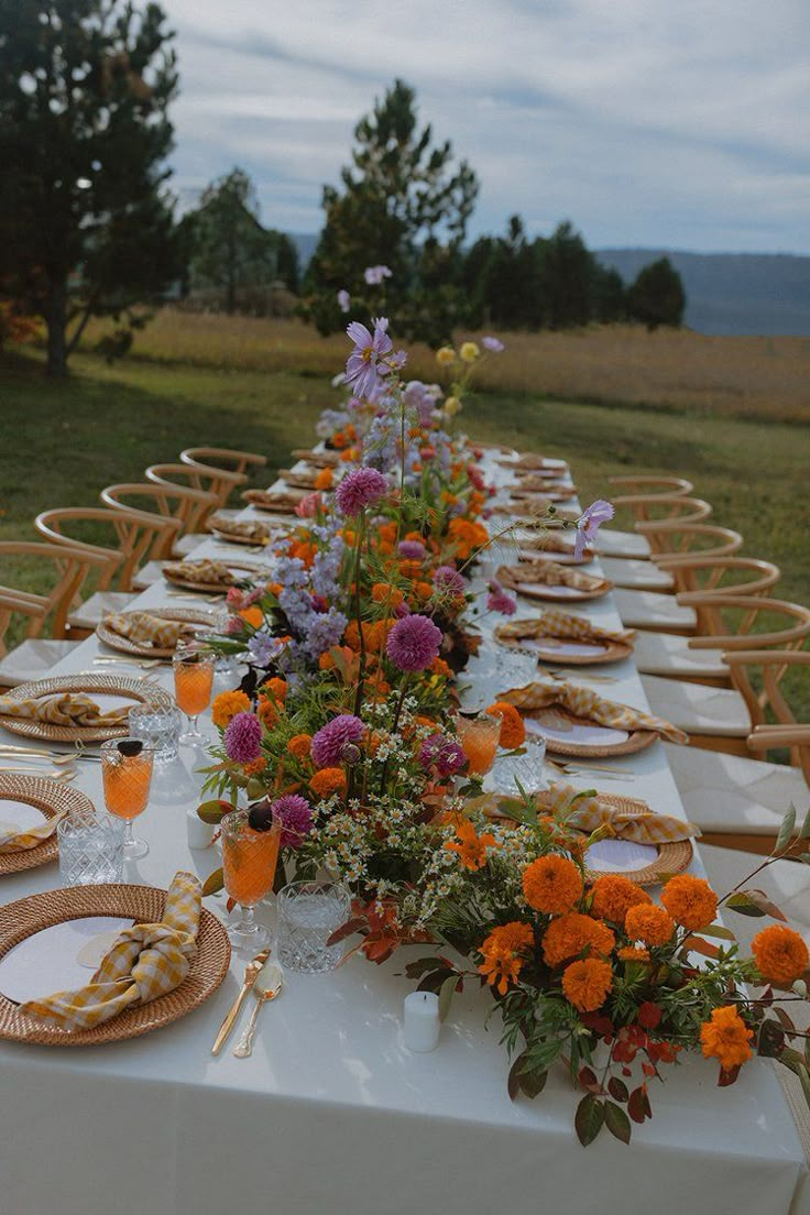 a long table is set up with flowers and plates for an outdoor dinner or party