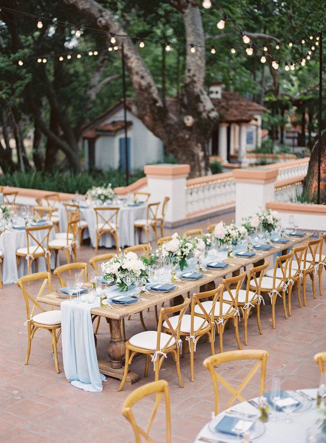 the table is set with white flowers and blue linens for an outdoor wedding reception