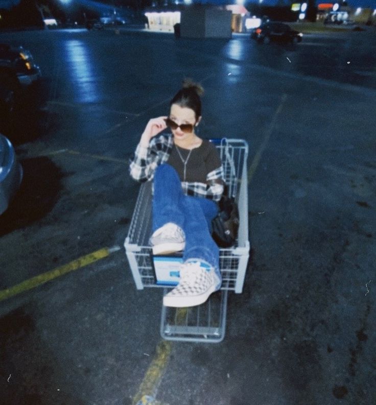 a woman sitting in a shopping cart with her feet up on the floor and wearing sunglasses