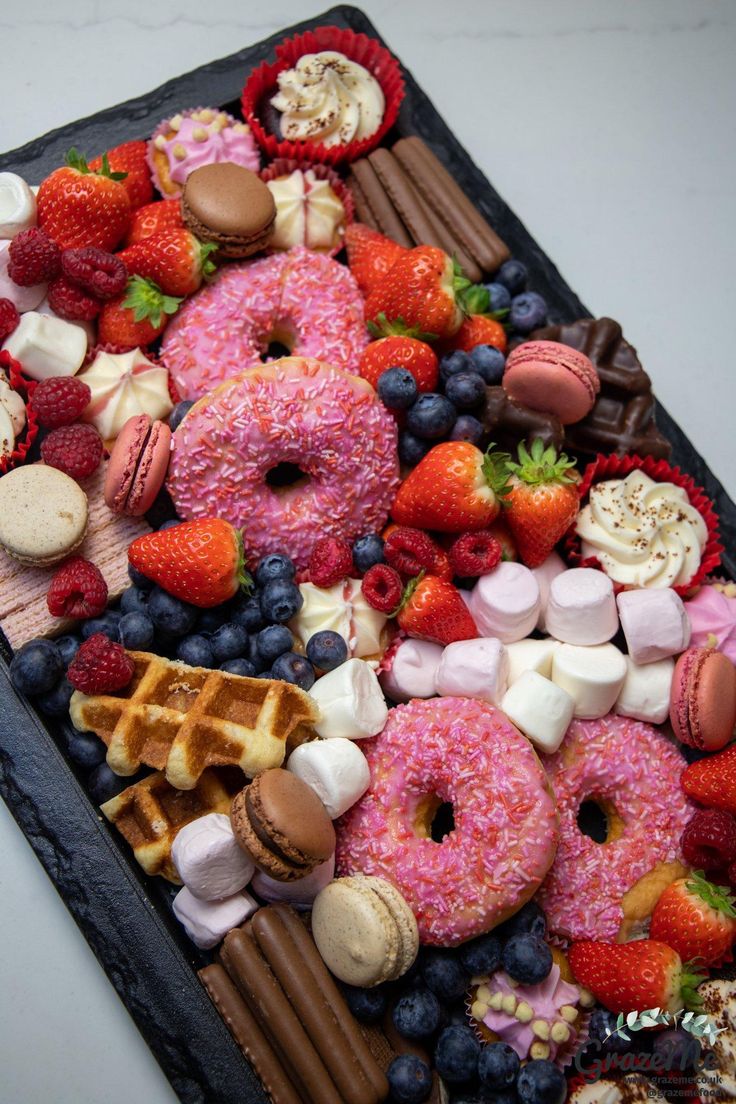 a platter filled with donuts, strawberries, and other desserts on top of chocolate sticks