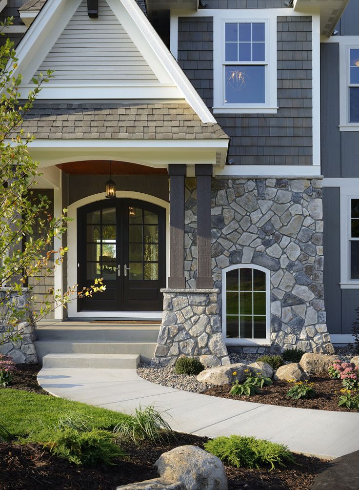 the front entrance to a house with stone and wood trimming on it's sides