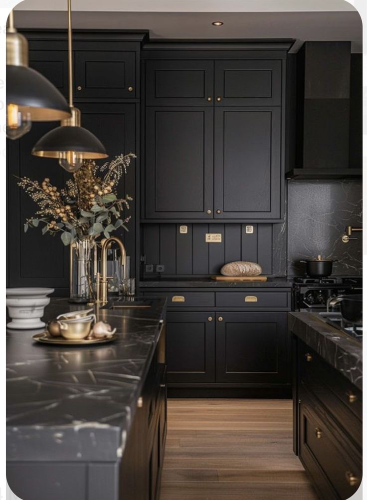 a large kitchen with black cabinets and marble counter tops, gold accents on the island