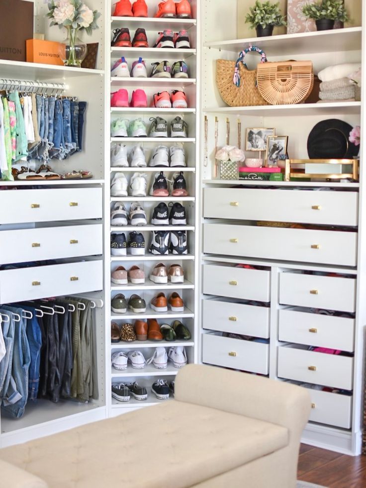 an organized closet with white drawers and lots of shoes on the shelves in front of it