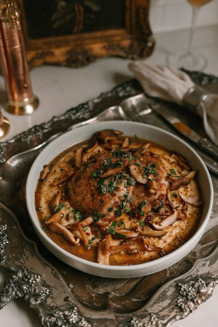 a white bowl filled with food on top of a metal tray next to silverware