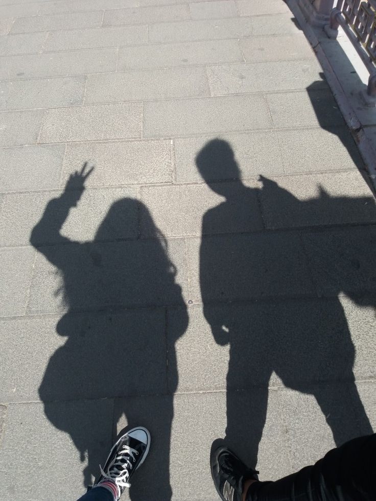 the shadow of two people standing next to each other with their hands in the air