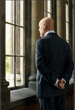 a bald man standing in front of a window