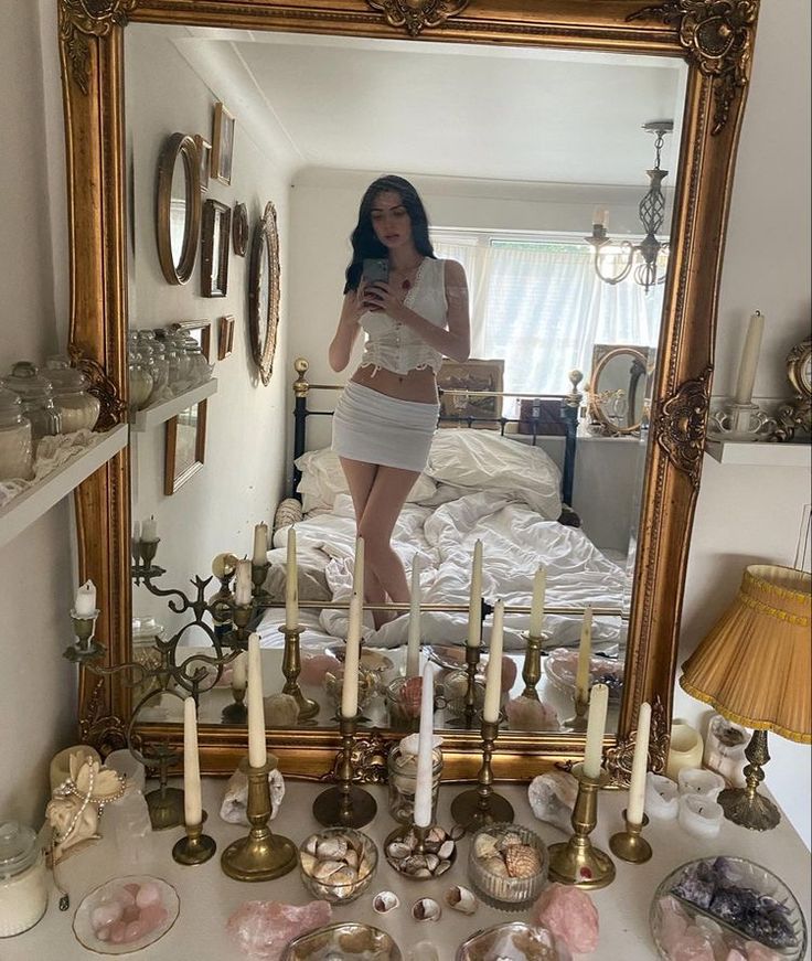 a woman taking a selfie in front of a mirror with candles on the table