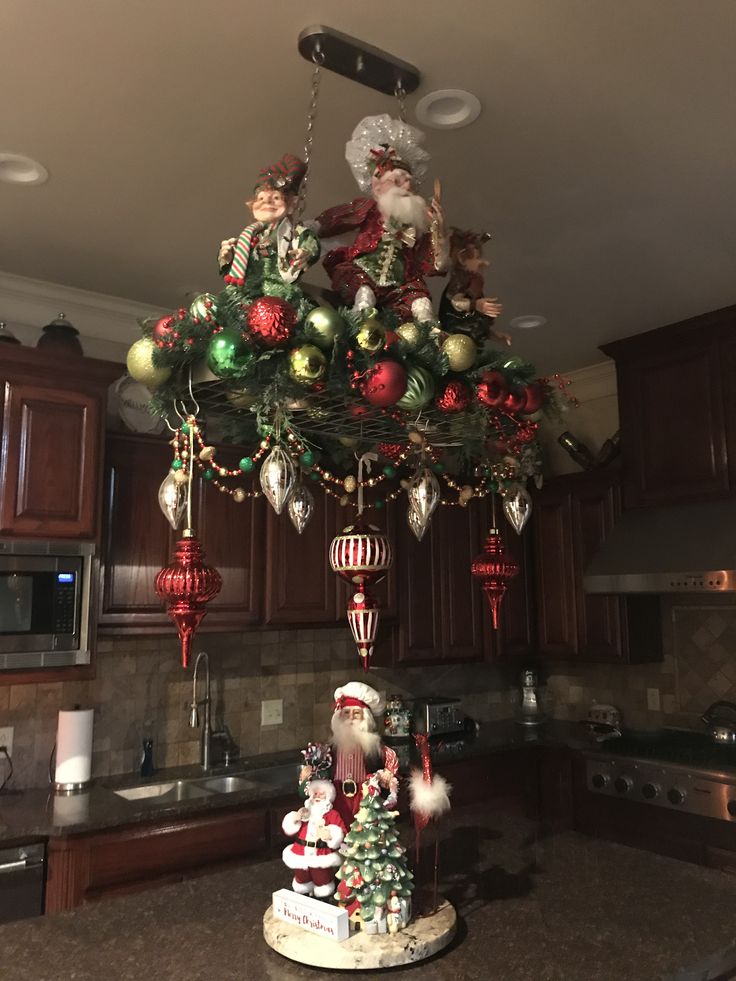 a christmas tree with ornaments hanging from it's top in a kitchen next to an oven