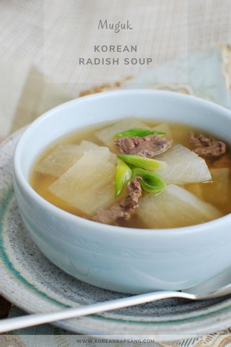 a white bowl filled with soup on top of a plate next to a fork and napkin