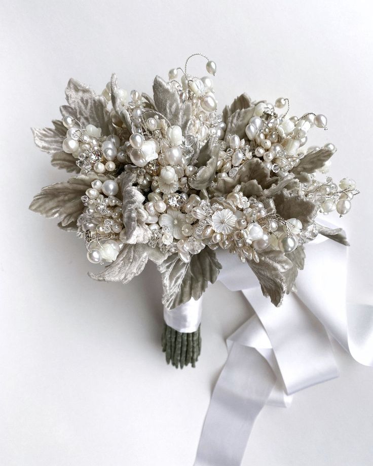 the bridal bouquet is adorned with pearls and leaves