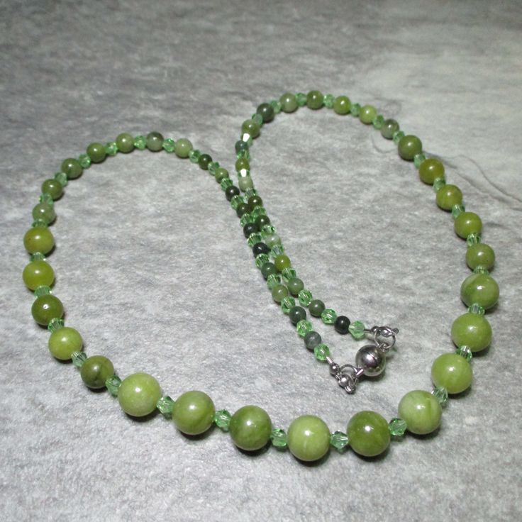 A charming necklace of Sothern Green Jade and green Czech Crystals. Green Czech Crystal bicone beads run the length of the necklace alternating with graduated sizes of Jade beads. At each end of the necklace the Crystals alternate with ten 4mm Jade beads, then with seven 6mm Jades, then with five 8mm Jade beads finally in the centre of the necklace the Crystal beads alternate with nine 10mm green Jade beads. All the metal work is Stainless Steel including the magnetic clasp and the earwires on the free matching earrings. Necklace and earring come enclosed within a grey fine Velvet bag. The necklace is approx. 59.5cm (23.5in) long. Jade supposedly will bring you luck in love and is believed to promote fidelity. Jade supports the reproductive system in both male and female and it is supposed Green Crystal Necklaces With Round Hand-strung Beads, Green Crystal Necklaces With Polished Round Beads, Green Polished Round Bead Necklaces, Green Gemstone Beaded Necklaces, Hand-strung Green Jade Beads, Green Single Strand Necklace With Round Beads, Green Crystal Necklaces With Round Gemstone Beads, Green Jade Beads For Jewelry Making, Green Crystal Necklace With Round Gemstone Beads