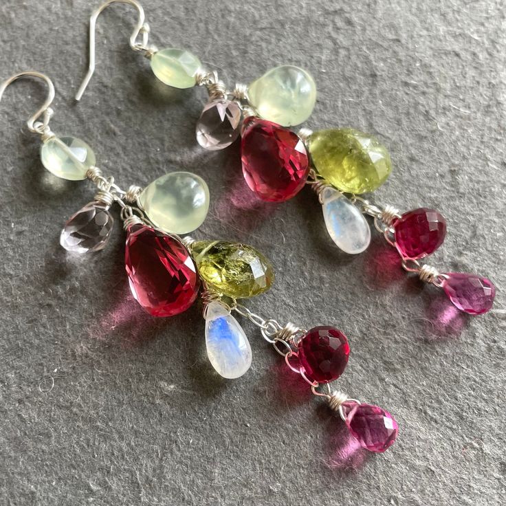 See VIDEO on instagram 2/23. From an artisan sterling silver earwires and chain I have wired in sterling silver prehnite, pink quartzes, moonstone, green garnet in a delightful dangle. There may be some variation in the green garnets from pair to pair as they are all slightly different shades. The chain, earwires and all wiring is sterling silver. The approximate length is 3”. I can also do these in other metals. The default is shown here. For any metal or earwire upgrades please shop directly from the main site, shirzay.com and select them. Whimsical Sterling Silver Drop Earrings, Silver Briolette Earrings With Gemstone Accents, Bohemian Sterling Silver Briolette Earrings, Sterling Silver Bohemian Briolette Earrings, Silver Briolette Natural Gemstones, Handmade Silver Briolette Gemstones, Green Garnet, Colorful Jewelry, Pink Quartz