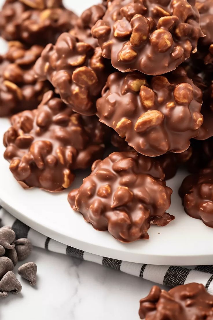 chocolate covered cookies on a white plate with nuts in the middle and more scattered around