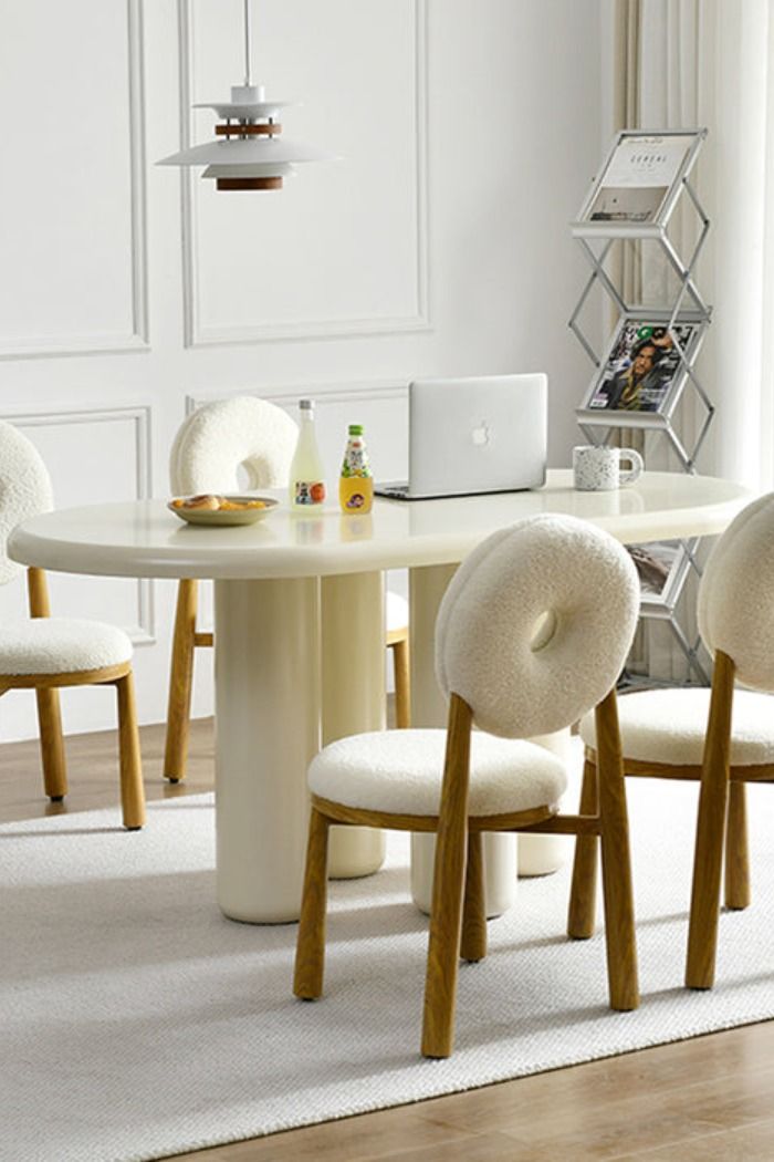 a dining room table with four chairs and a laptop on the other side, in front of a white wall