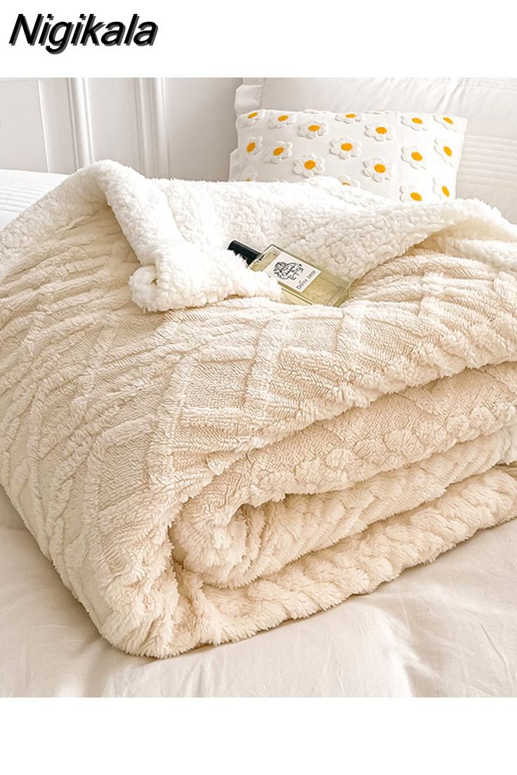 a white blanket sitting on top of a bed covered in blankets and pillows next to a pillow