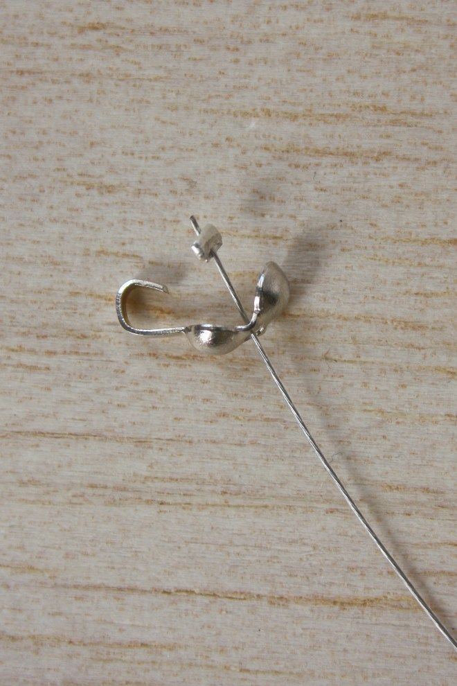 a piece of metal wire sitting on top of a wooden table next to a pair of scissors