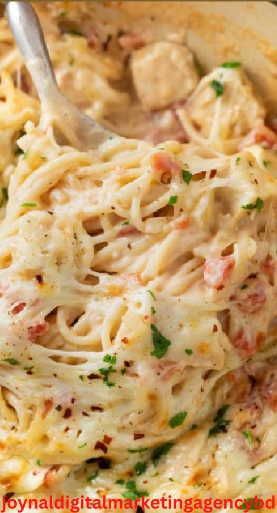 a close up of a bowl of food with pasta and meat in it, with a spoon