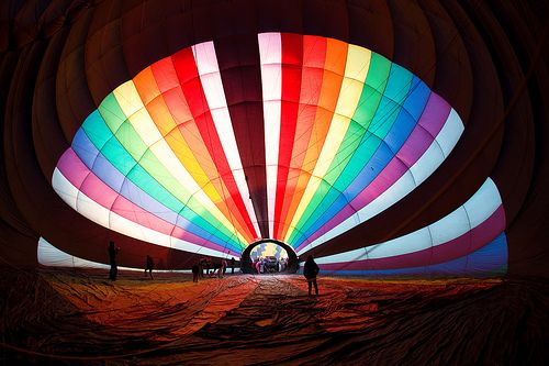 the inside of a hot air balloon that is lit up with colorful lights and people standing in it