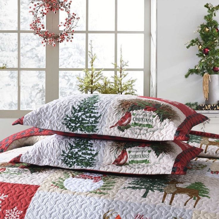 three pillows are stacked on top of each other in front of a window with christmas decorations