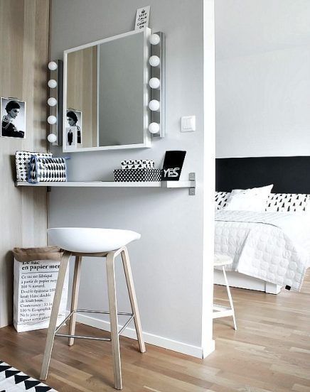 a bedroom with a stool, mirror and lights on the wall above it's bed