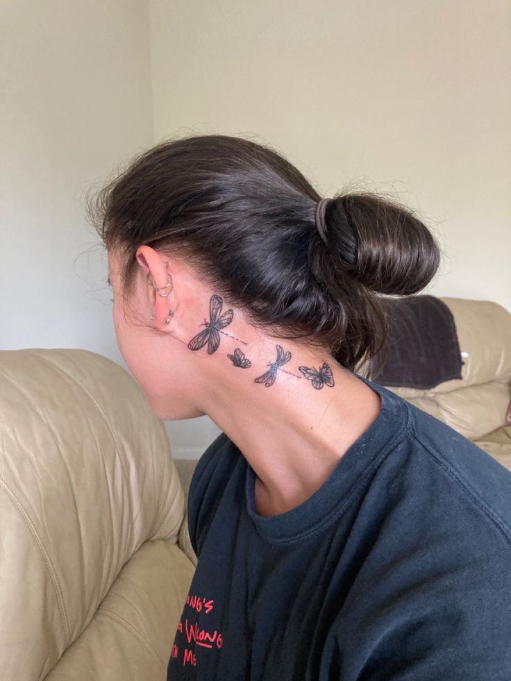 a woman with a butterfly tattoo on her neck and behind her head is a cat