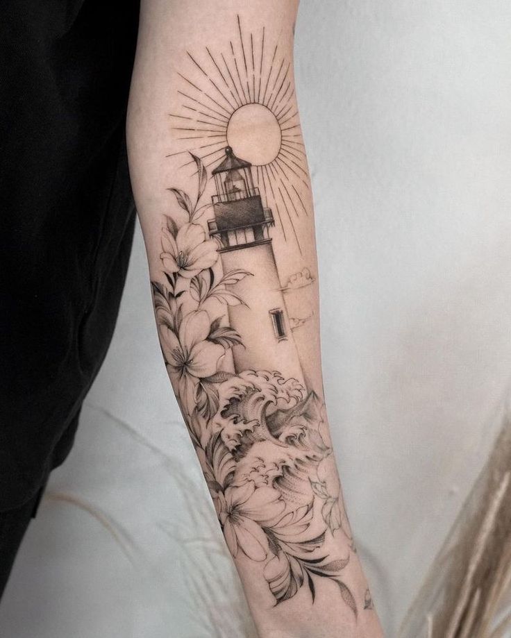 a woman's arm with a lighthouse and flowers on it