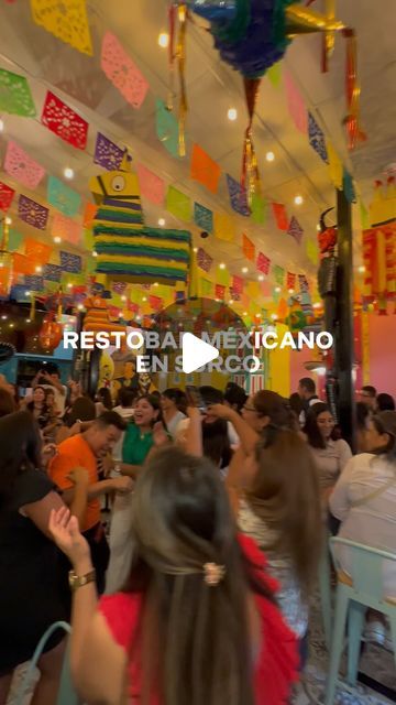 a group of people sitting at tables in a room with flags hanging from the ceiling