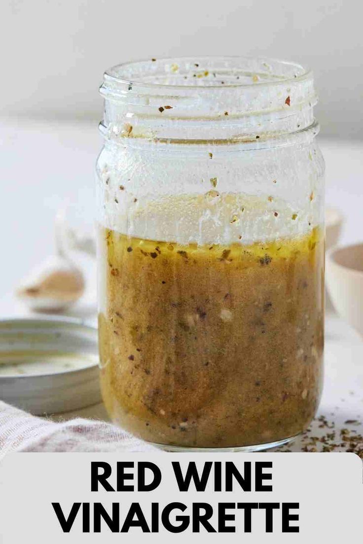 a jar filled with red wine vinaigrete sitting on top of a table