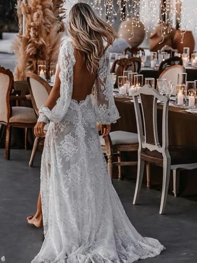 a woman in a white dress standing next to a table with candles and flowers on it