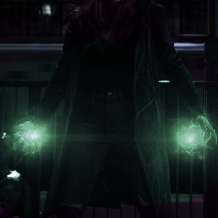 a woman standing in the dark with green lights on her hands