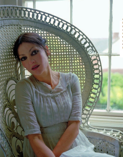 a woman sitting in a wicker chair next to a window