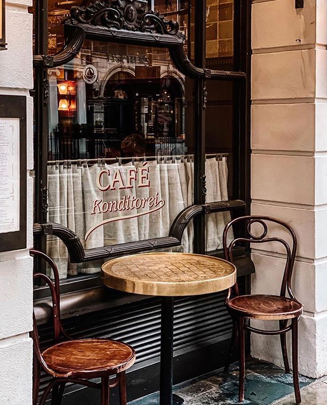 two wooden chairs sitting at a table in front of a cafe