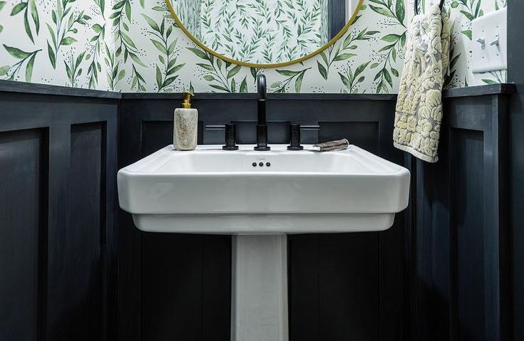 a white sink sitting under a bathroom mirror next to a wall mounted faucet