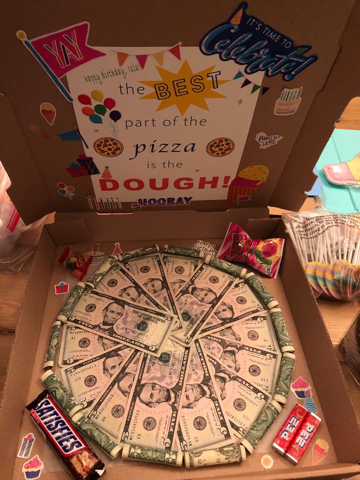 a pizza in a box with candy on the side and a sign that says best part of the pizza is the dough